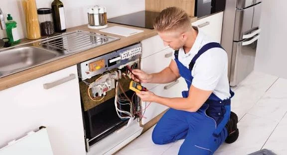 Technician testing an open dishwasher panel with a multimeter